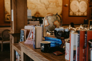 Vintage globe, camera, and books on wooden shelf for home decor styling