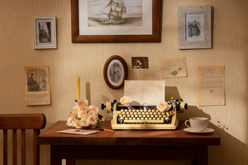 Vintage typewriter with roses on wooden desk, framed art, and cozy home decor