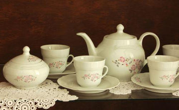 Elegant floral tea set with teapot, cups, and saucers on lace doily for home decor