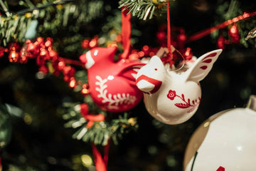 Red and white ceramic bird ornaments on a Christmas tree with festive lights