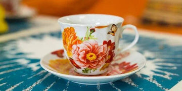 Floral tea cup and saucer on blue patterned tablecloth, home decor accent