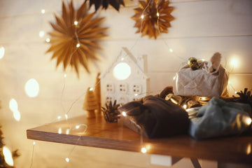 Cozy holiday decor with fairy lights, star ornaments, and wrapped gifts on wooden shelf