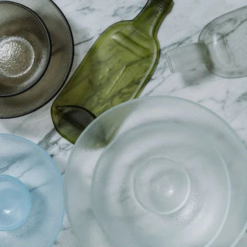Stylish glassware and green bottle on marble surface for modern home decor