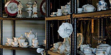 Elegant vintage teacups, plates, and porcelain decor displayed on rustic shelves for home styling.
