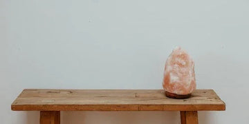 Pink Himalayan salt lamp glowing softly on rustic wooden table, cozy home decor accent