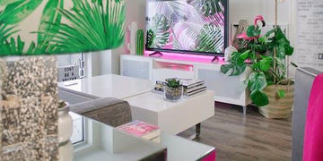 Tropical leaf lampshade and pink flamingo decor in modern living room with white furniture and green plants