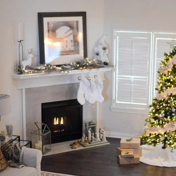 Cozy holiday living room with lit fireplace, decorated mantel, and glowing Christmas tree