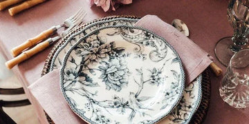 Elegant floral dinnerware set with black and white botanical print, styled on blush napkin for chic table setting