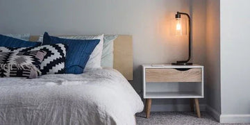 Stylish modern bedside table with lamp, cozy bed, and patterned pillows for home decor