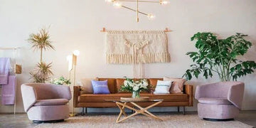 Modern living room with velvet armchairs, leather sofa, macrame wall art, and indoor plants for cozy home decor
