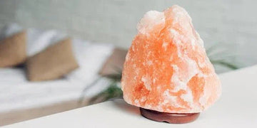 Himalayan salt lamp glowing softly on bedside table, warm ambient lighting for cozy bedroom decor