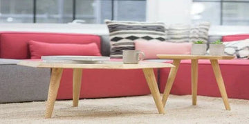 Modern wooden coffee table with books and mug, styled with red sofa and patterned pillows for cozy home decor