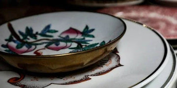 Elegant floral-patterned porcelain bowl with gold rim, styled on decorative plates for home decor