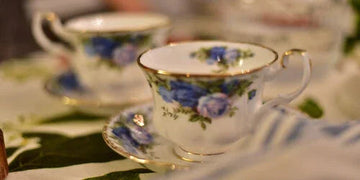 Elegant floral teacup with blue roses and gold trim, perfect for vintage home decor