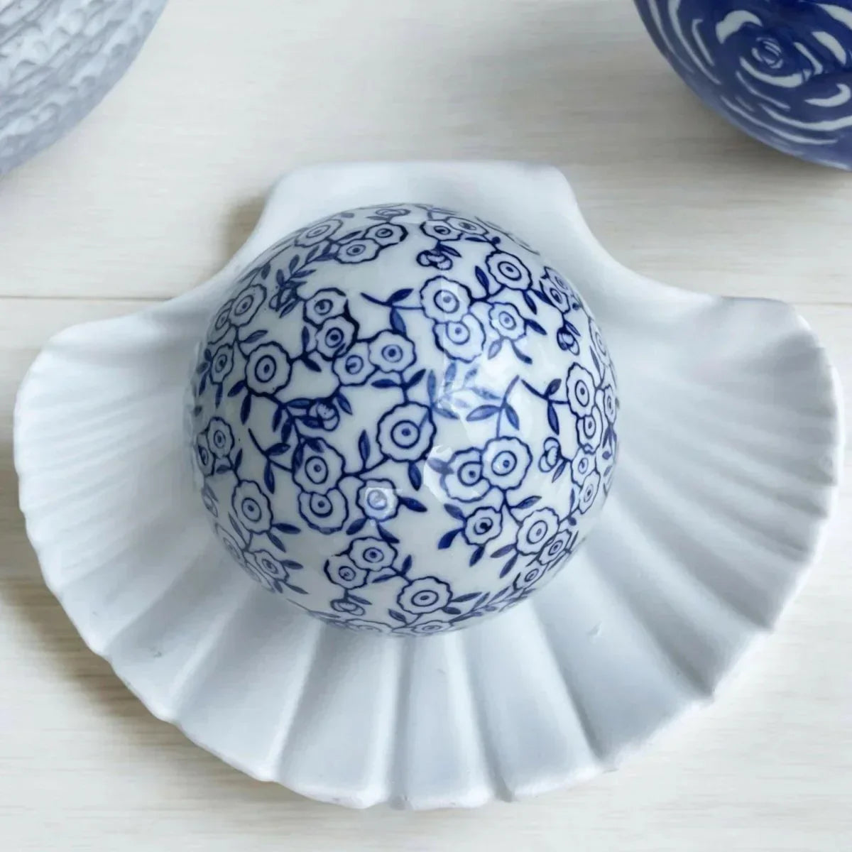 Blue and white floral ceramic deco ball on white shell dish, elegant home decor