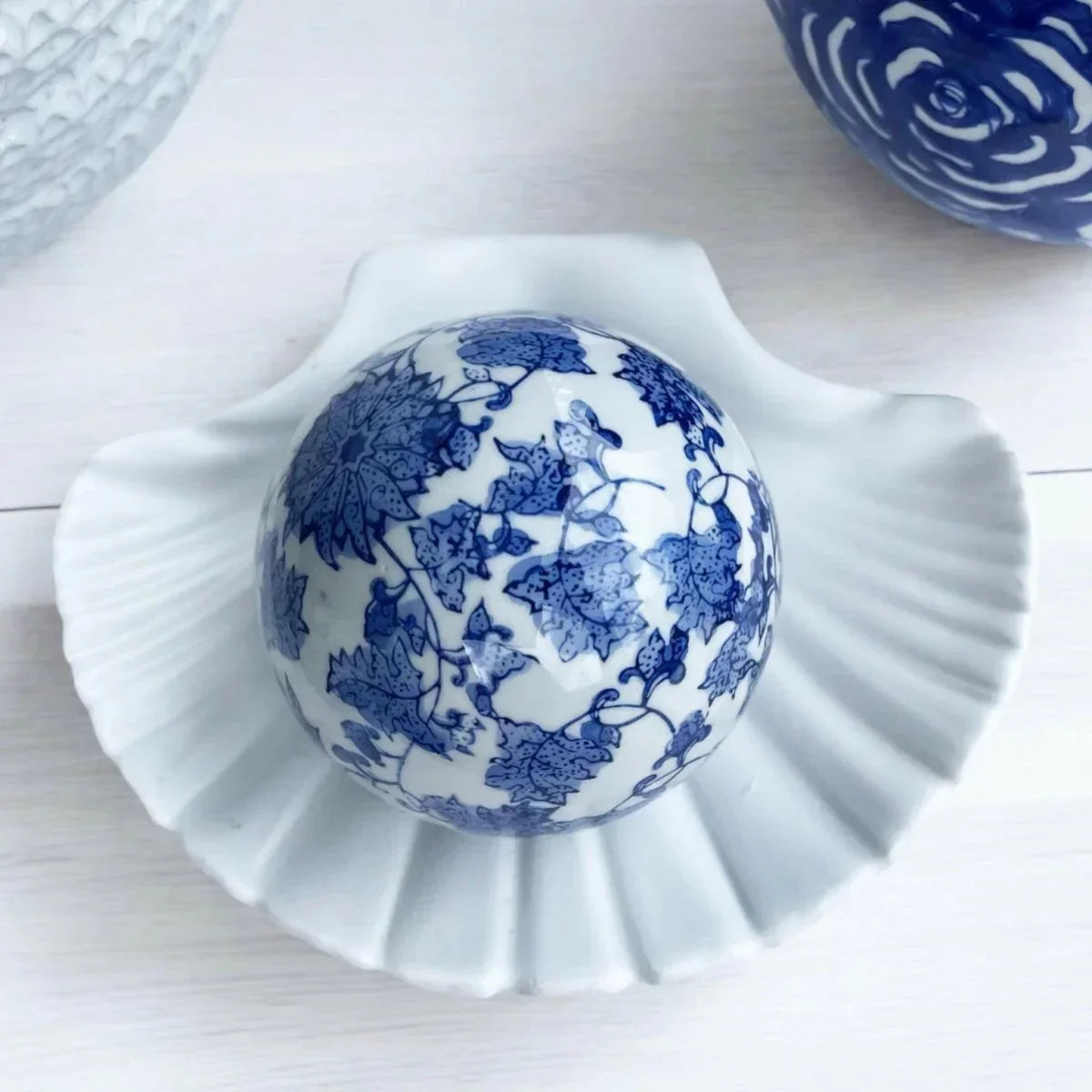 Blue and white decorative ceramic ball with floral pattern in scallop shell dish, home decor