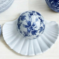 Blue and white ceramic decorative ball with floral pattern on a white shell dish, home décor