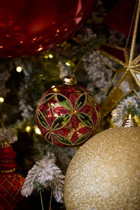 Red and green beaded Christmas ornament on flocked tree with gold glitter baubles