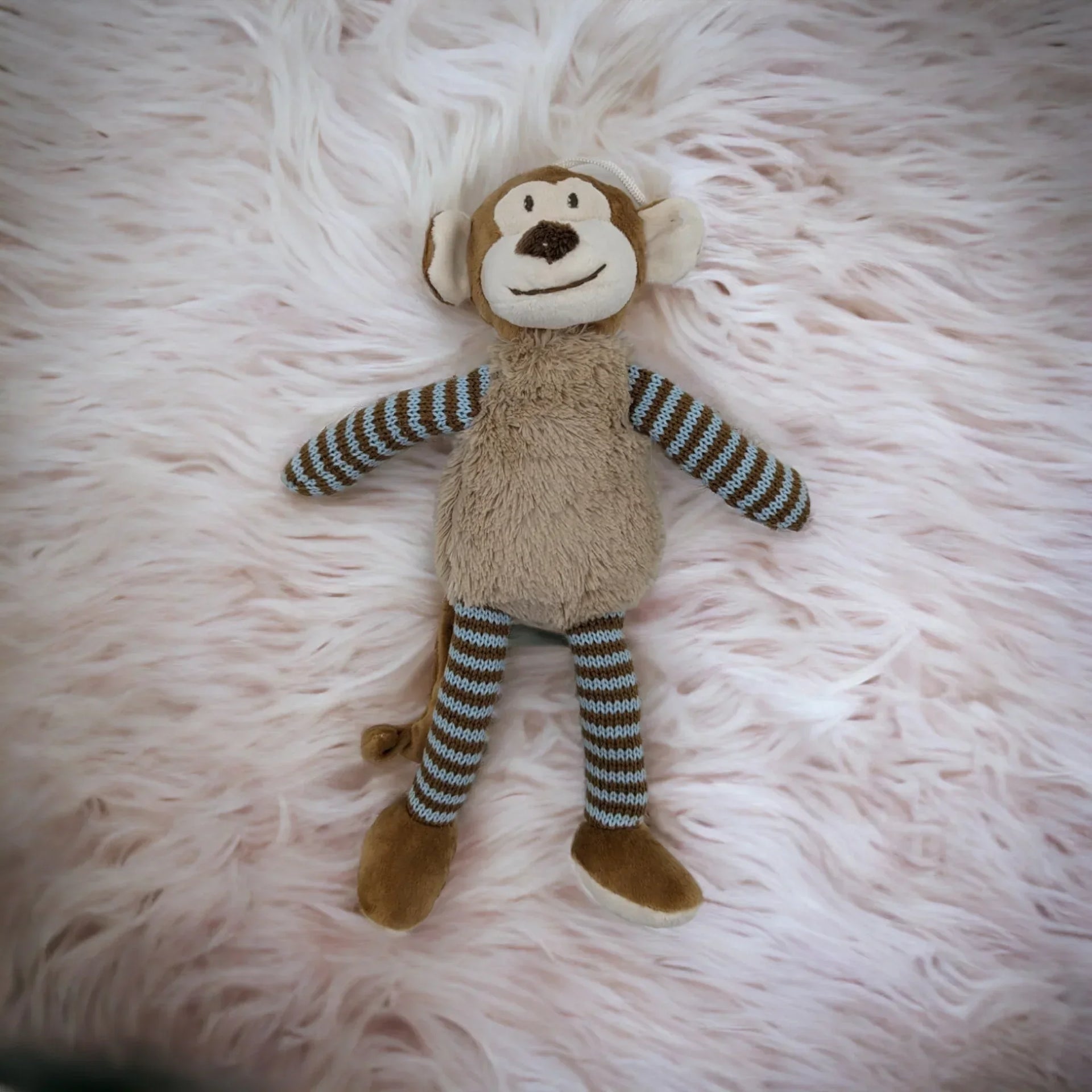 Soft plush monkey toy with striped arms and legs, perfect for nursery decor or baby gifts