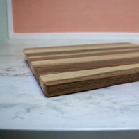 Striped wooden cutting board on marble countertop, perfect for kitchen décor and food prep