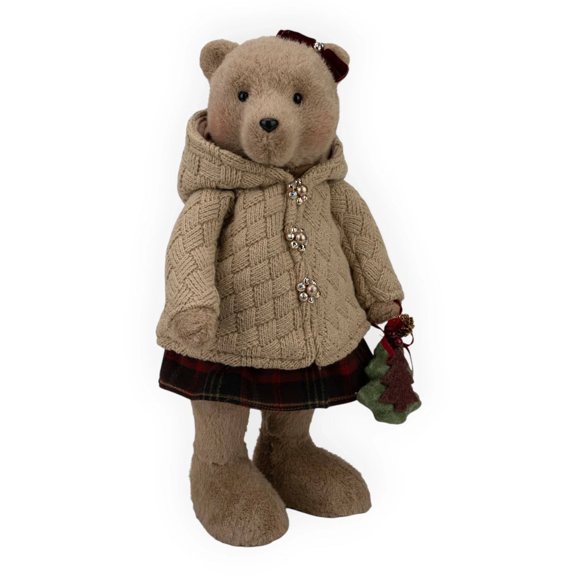 Charming teddy bear in cozy cable knit coat, plaid skirt, holding festive Christmas tree ornament, perfect for holiday home décor.