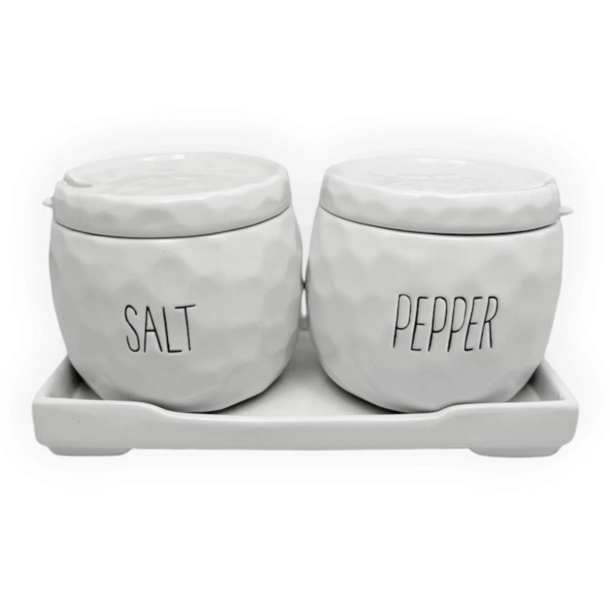 A pair of white textured ceramic spice jars labeled 'SALT' and 'PEPPER' sitting on a matching white ceramic tray against a white background.