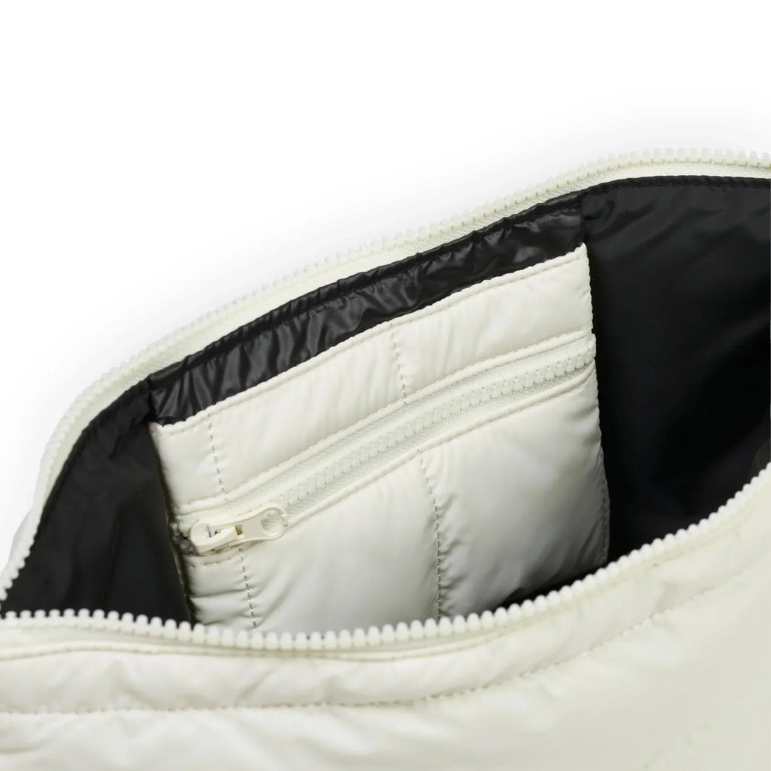 White quilted bag interior with black lining and zippered pocket, showcasing organized storage design.