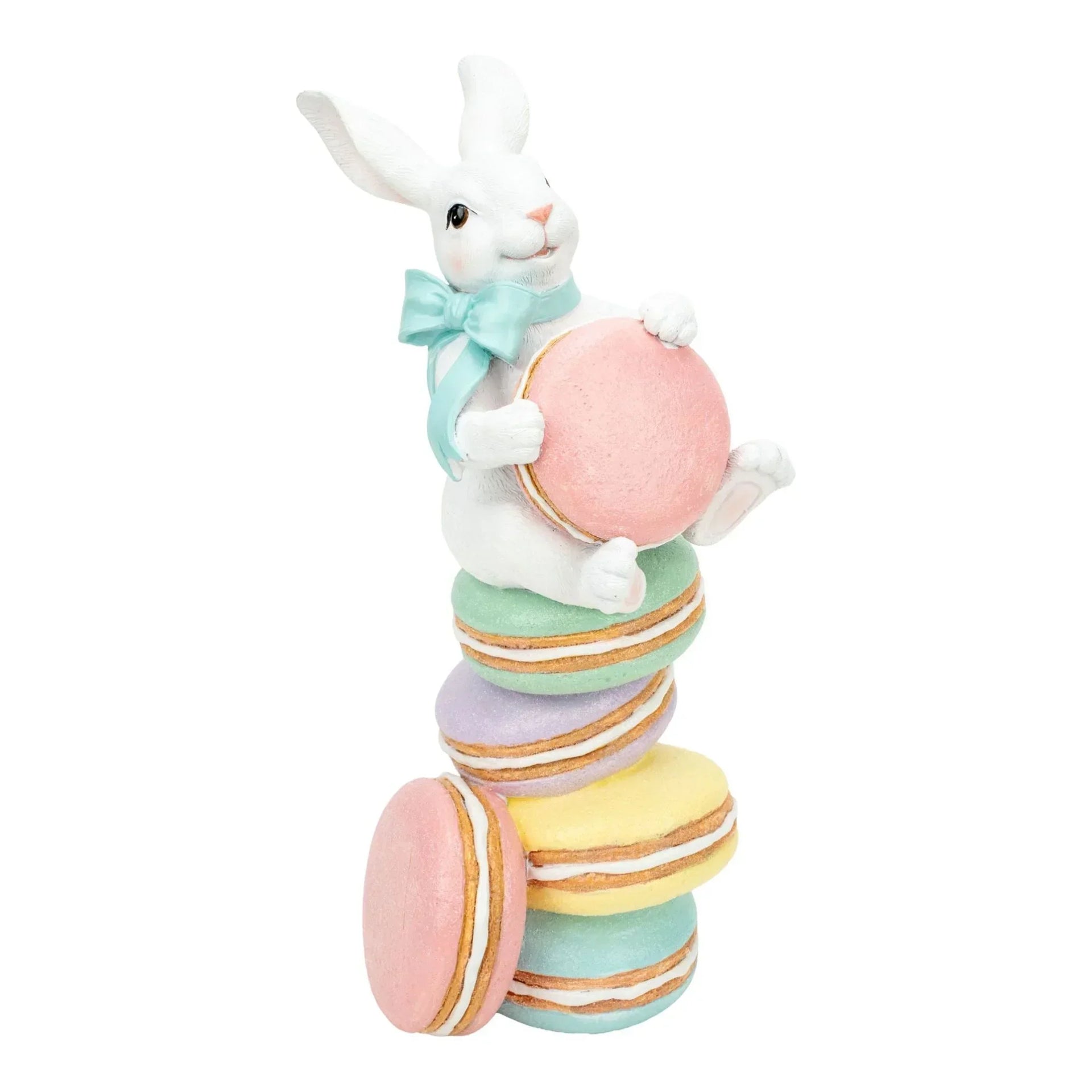 White bunny figurine with mint bow holding pink macaron, perched on pastel macaron stack for Easter home decor