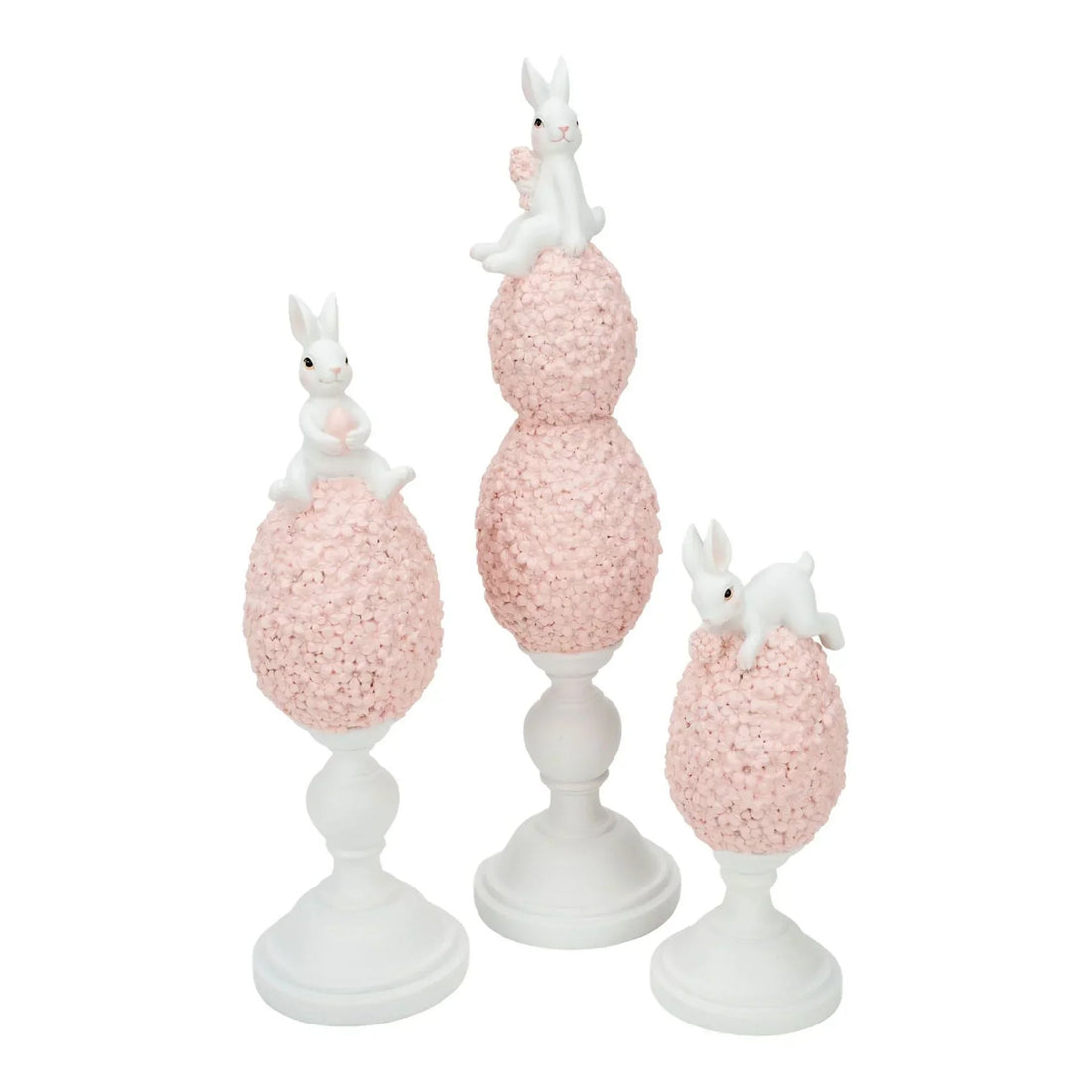 White bunny figurines atop pink floral eggs on pedestals, elegant home décor set