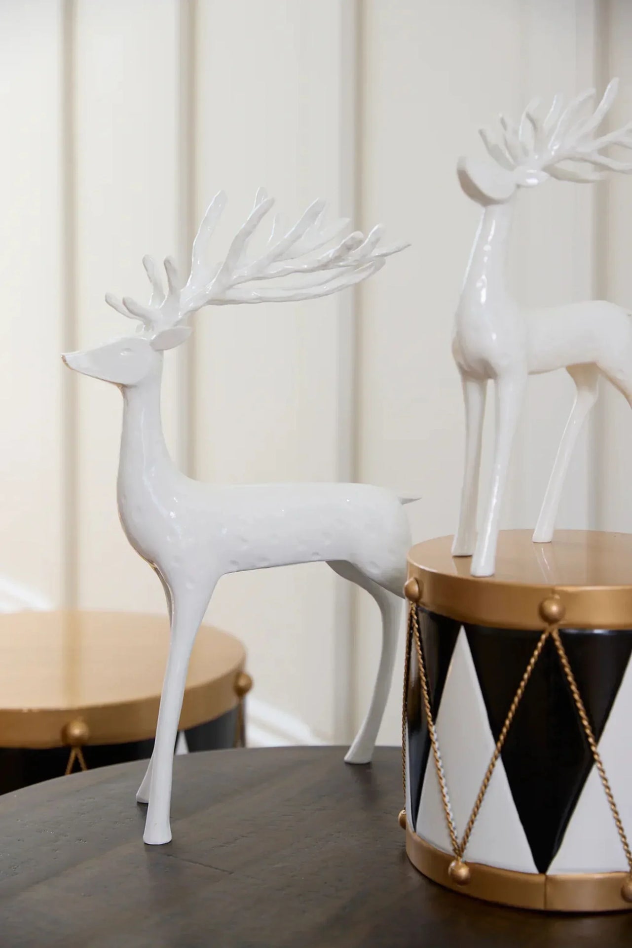 White ceramic deer figurines with intricate antlers, styled on a table with geometric decor accents.
