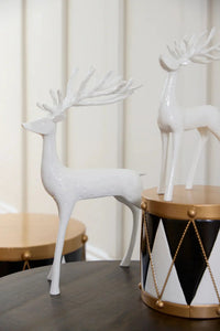 White ceramic deer figurines with antlers, modern home decor on dark wood table with geometric drum