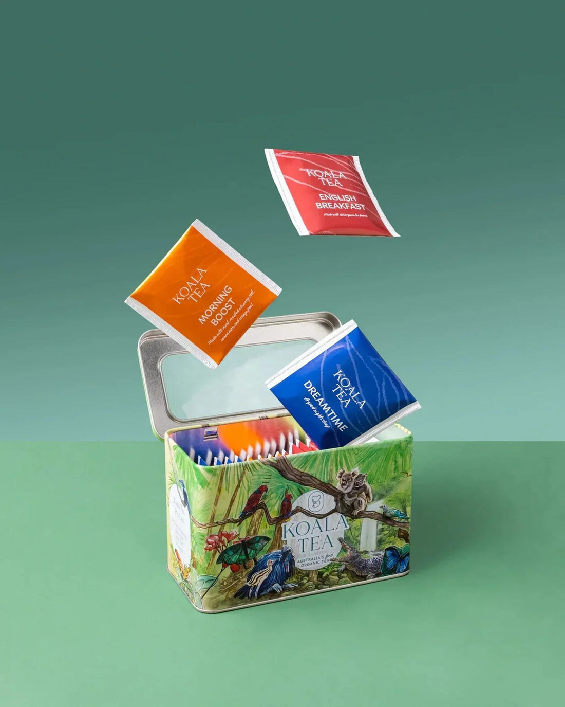 Koala Tea organic tea bags in colorful tin with koala and bird artwork, featuring Morning Boost, English Breakfast, and Dreamtime blends