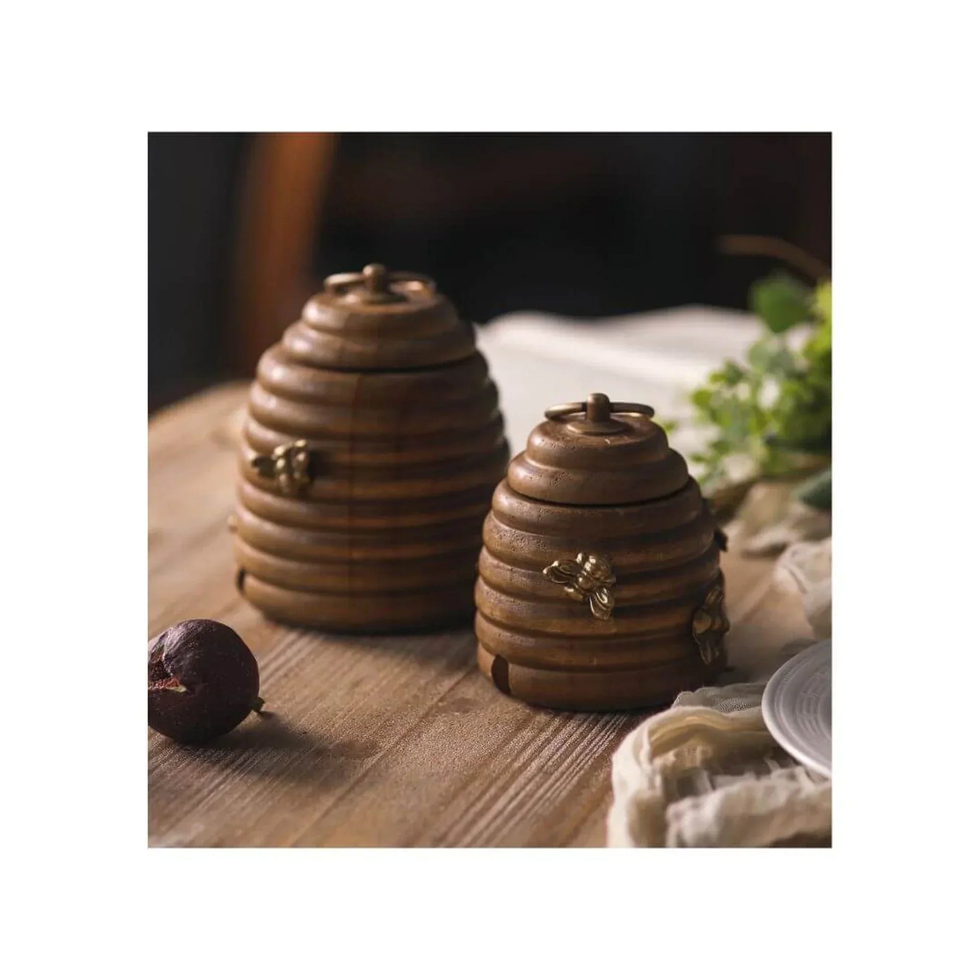 Rustic wooden beehive jars with brass bee accents, perfect for vintage home décor and kitchen storage.