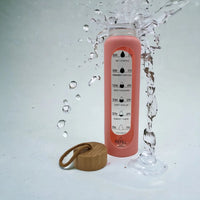 Pink motivational water bottle with time markers, bamboo lid, and splash effect for hydration tracking