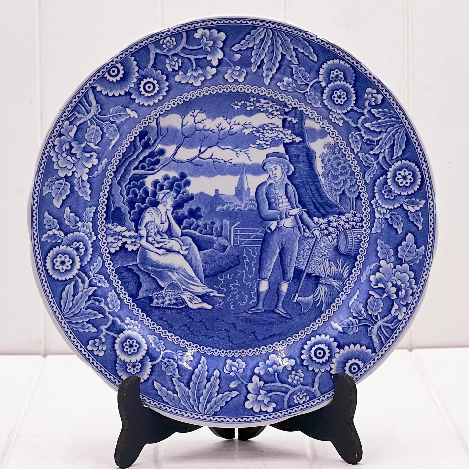 Blue and white decorative plate with vintage pastoral scene, floral border, ideal for home décor