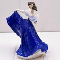 Elegant porcelain figurine of a woman in flowing blue gown, vintage home décor accent piece