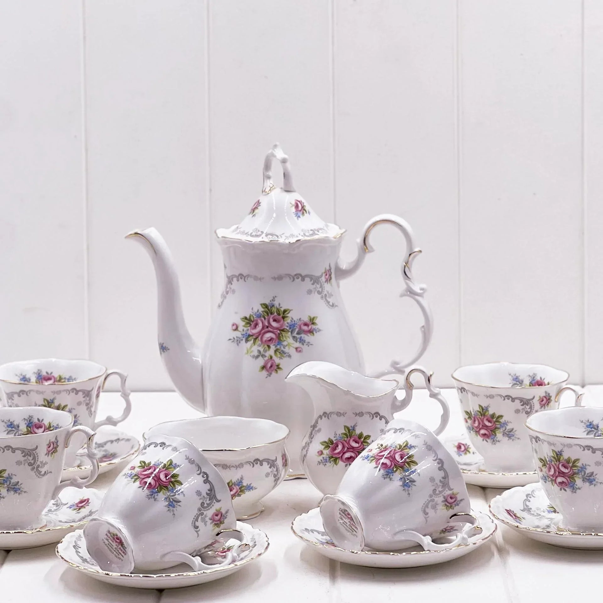Elegant floral tea set with pink roses, gold trim, teapot, cups, saucers, and creamer for vintage home décor