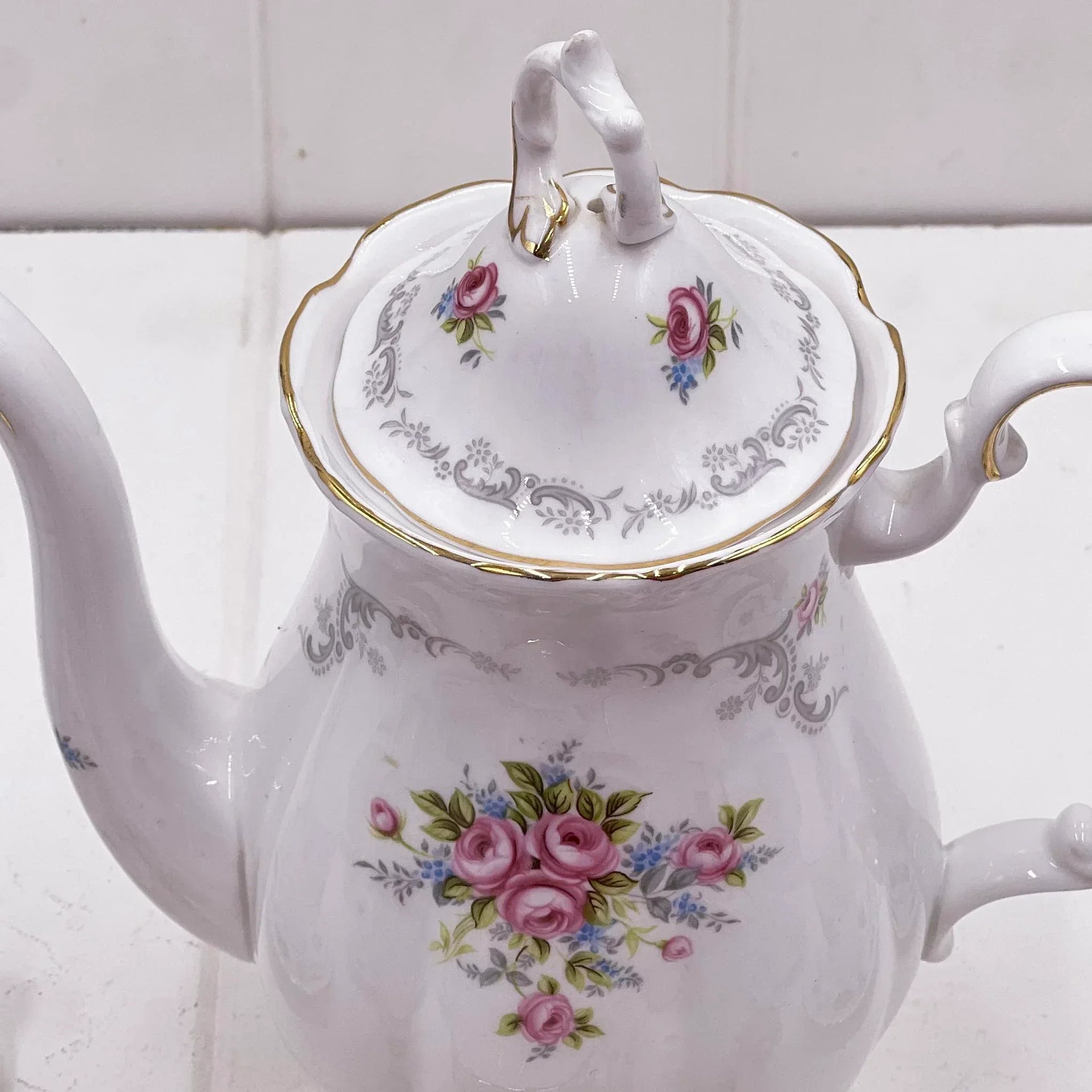 Elegant white porcelain teapot with pink rose floral design, gold trim, and vintage-style handle