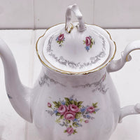 Elegant white porcelain teapot with pink rose floral design, gold trim, and vintage-style handle