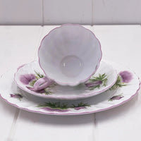 Vintage thistle-patterned porcelain teacup, saucer, and plate set with scalloped edges and purple accents
