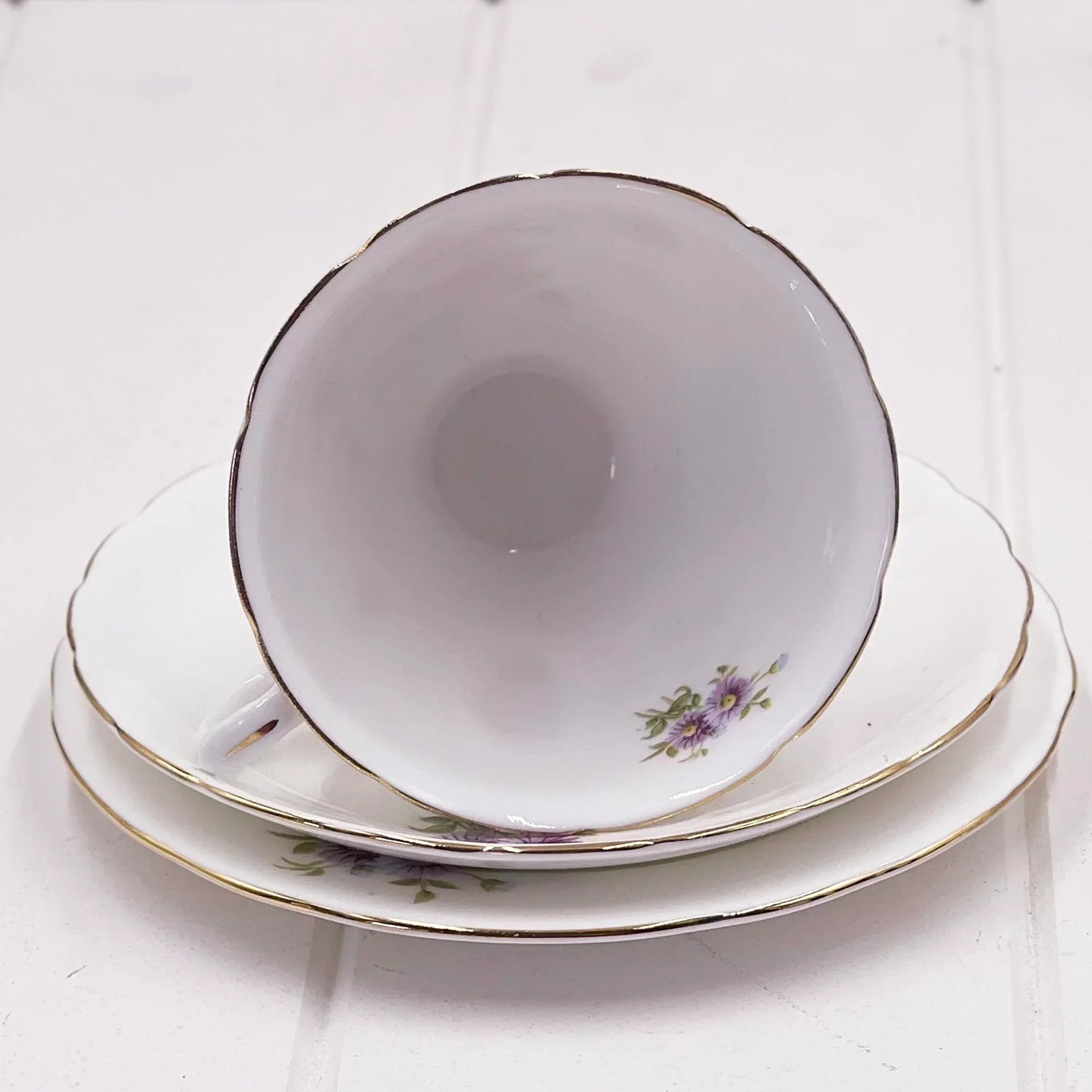 Elegant porcelain teacup and saucer set with purple floral design and gold trim, perfect for vintage home décor.