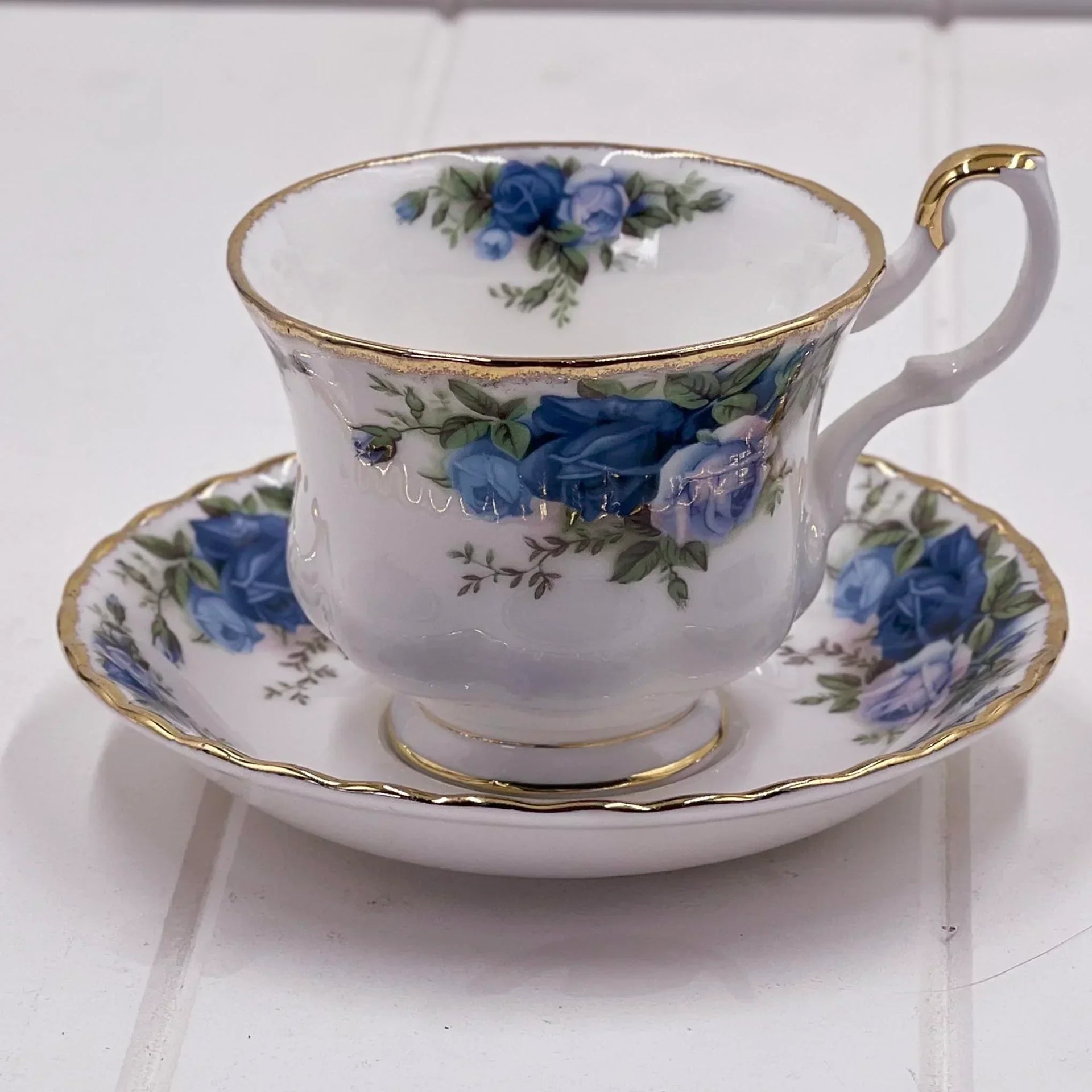 Elegant porcelain teacup and saucer with blue rose floral design and gold trim, vintage home decor