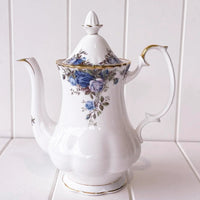 Elegant white porcelain teapot with blue rose floral design and gold trim, perfect for vintage home décor