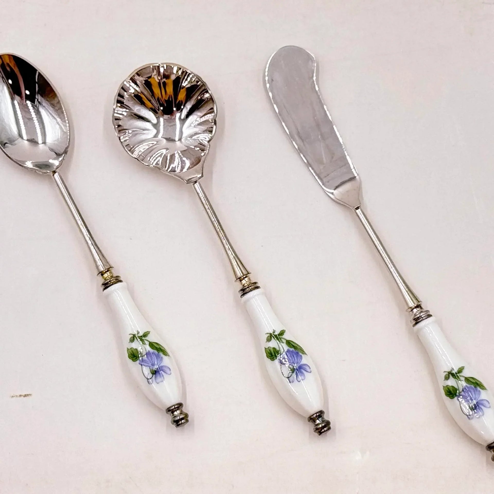 Elegant vintage serving set with floral porcelain handles and silver-toned metal, perfect for home décor