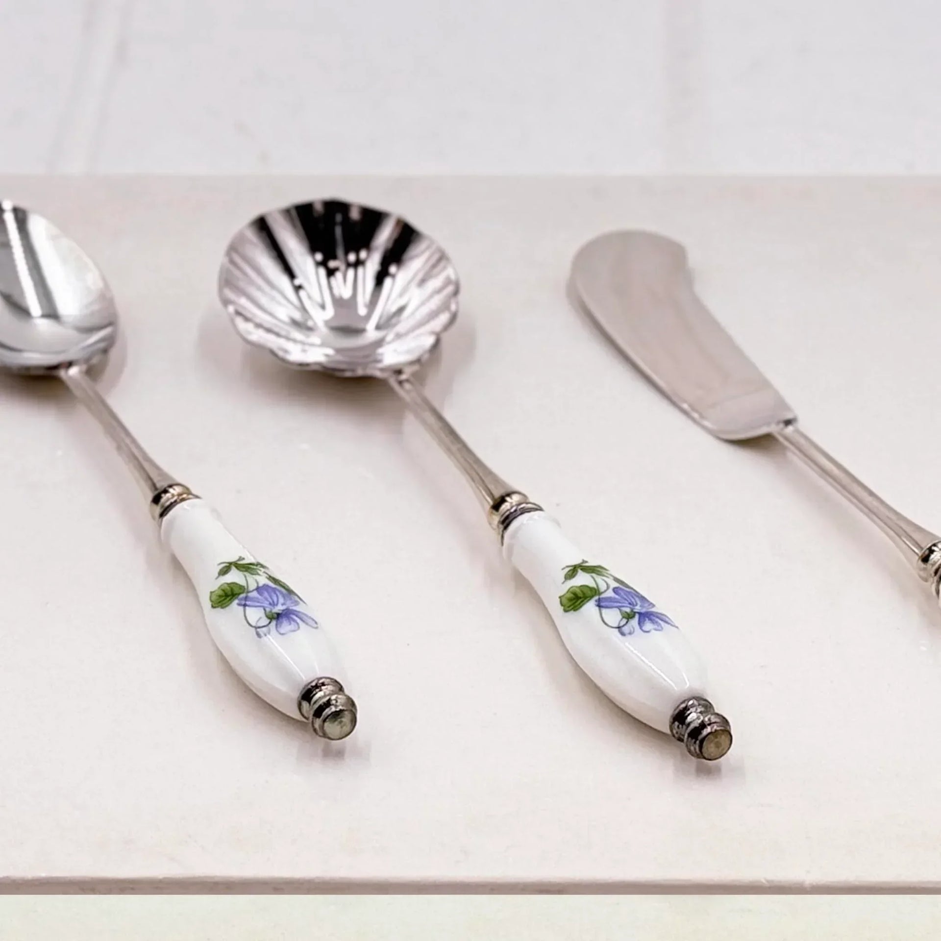 Elegant vintage serving set with floral porcelain handles and silver-toned metal, perfect for home décor