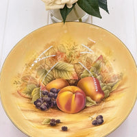 Vintage fruit platter with peaches, grapes, and berries on golden background, elegant home decor