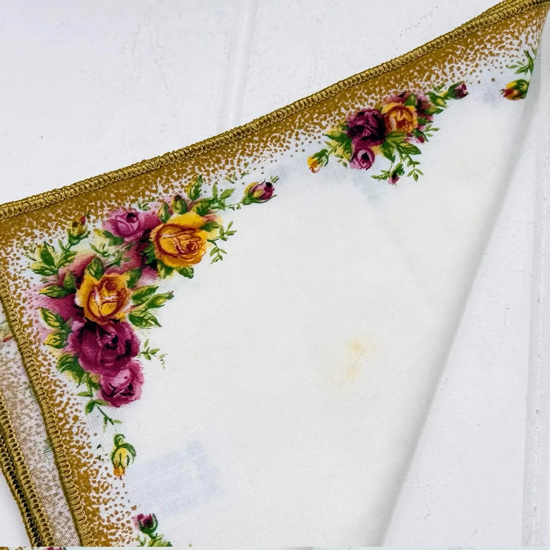 Vintage floral handkerchief with gold trim, featuring roses and greenery on white fabric for elegant home décor