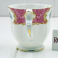 Elegant porcelain teacup with pink floral band, gold trim, and ornate handle, perfect for vintage home décor.