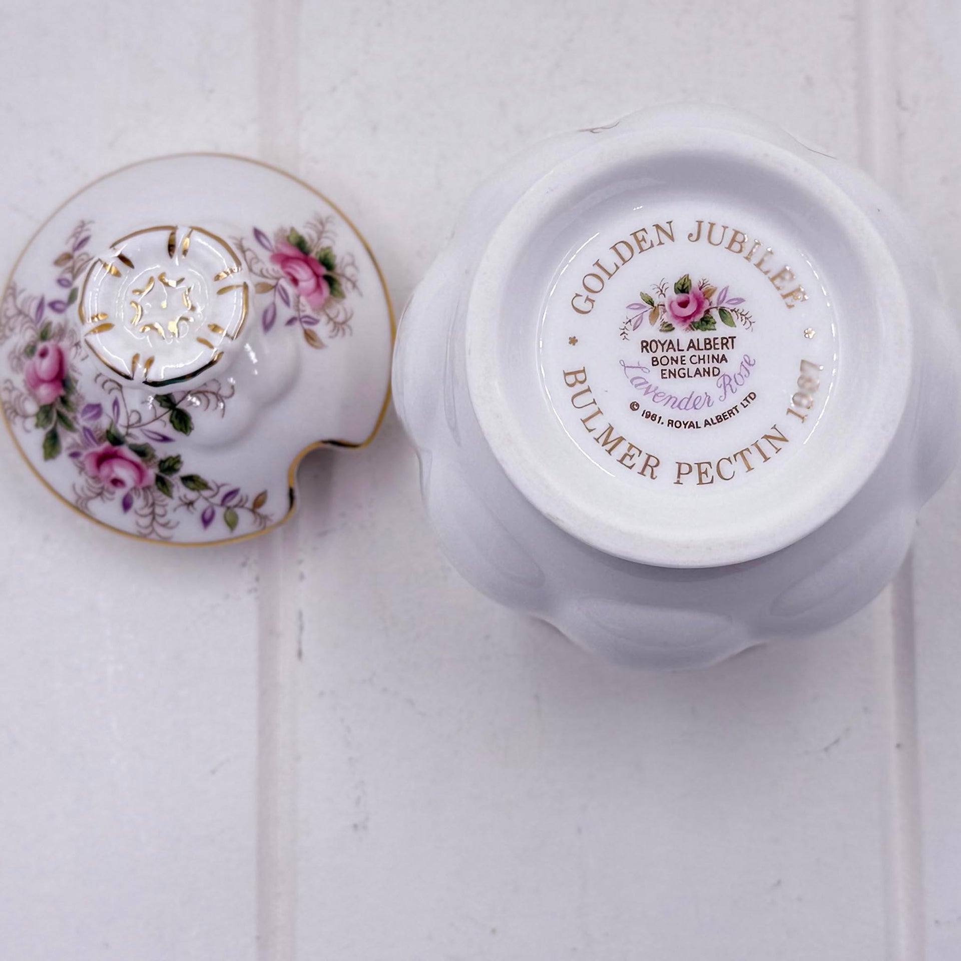 A white  Royal Albert lavender Rose bone china jam or sugar pot shown from the bottom and lid, featuring gold text reading 'GOLDEN JUBILEE BULMER PECTIN 1997' and pink floral detailing on the lid.