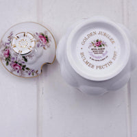 A white  Royal Albert lavender Rose bone china jam or sugar pot shown from the bottom and lid, featuring gold text reading 'GOLDEN JUBILEE BULMER PECTIN 1997' and pink floral detailing on the lid.